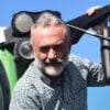 Tapasztalt gazdálkodó egy modern traktor mellett, a precíziós mezőgazdaság előnyeit kihasználva.
